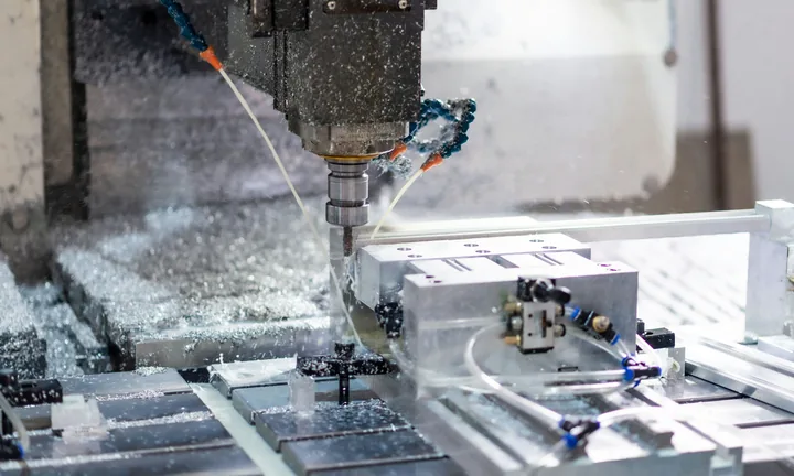 Fresadora CNC mecanizando una pieza de aluminio, con la viruta saltando